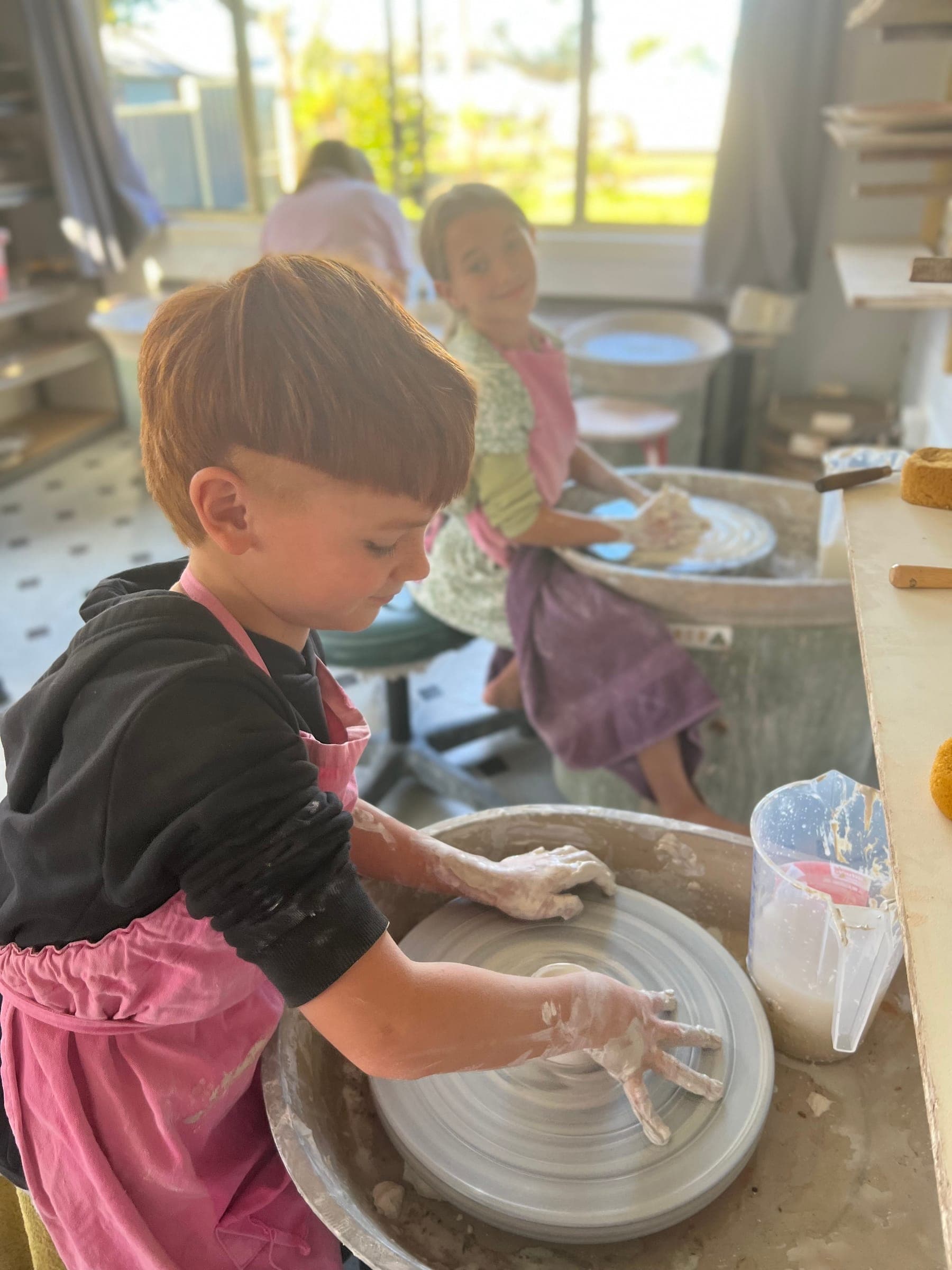 A young maker concentrating on centring clay on the wheel