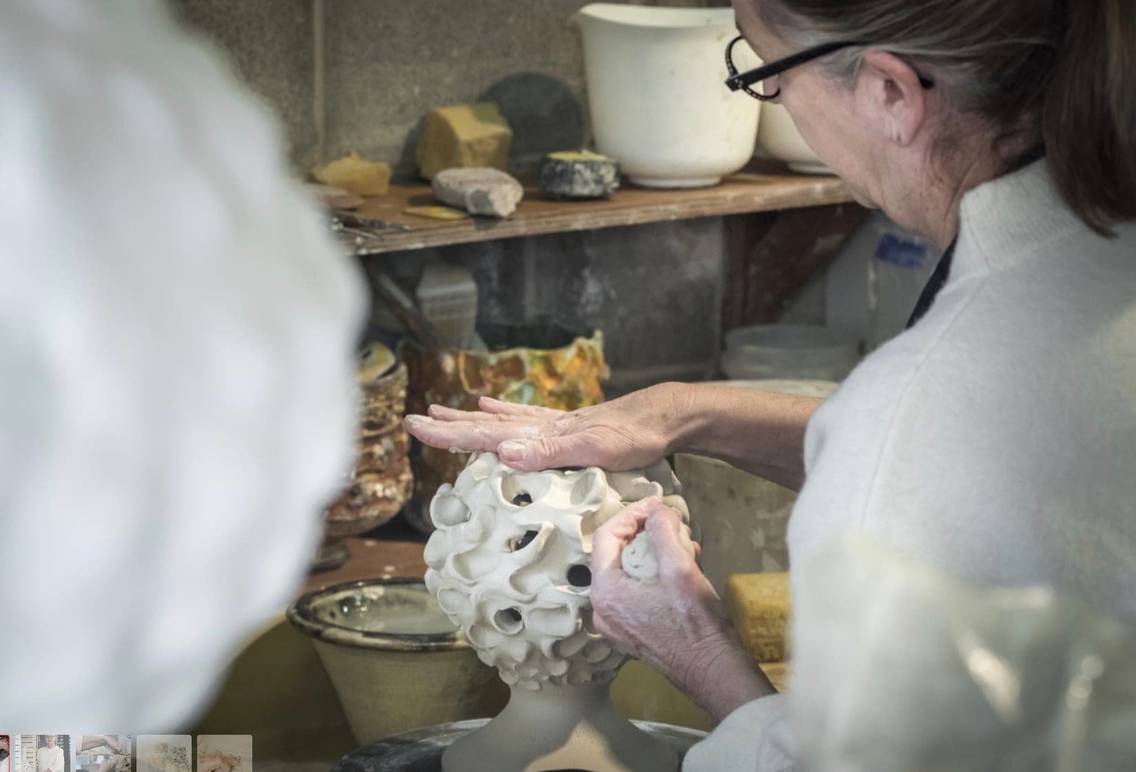 Hands adding small petals to a sculptural white porcelain form