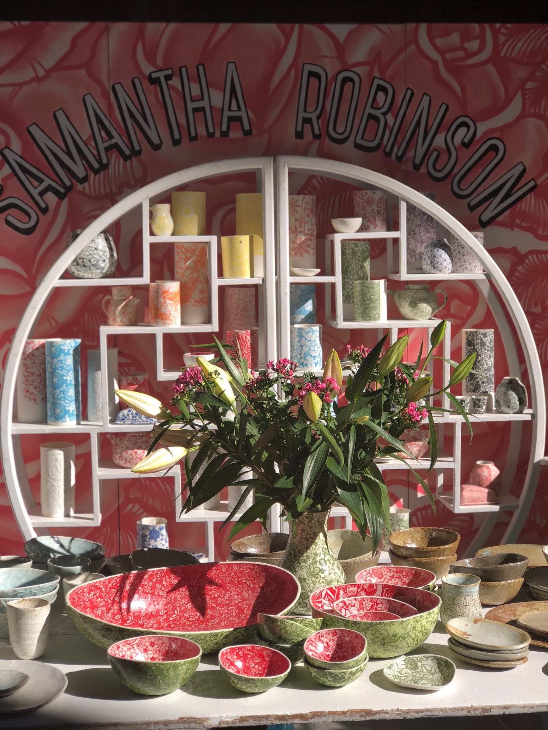 The pink Samantha Robinson mural wall with shelves of porcelain and a table of watermelon bowls